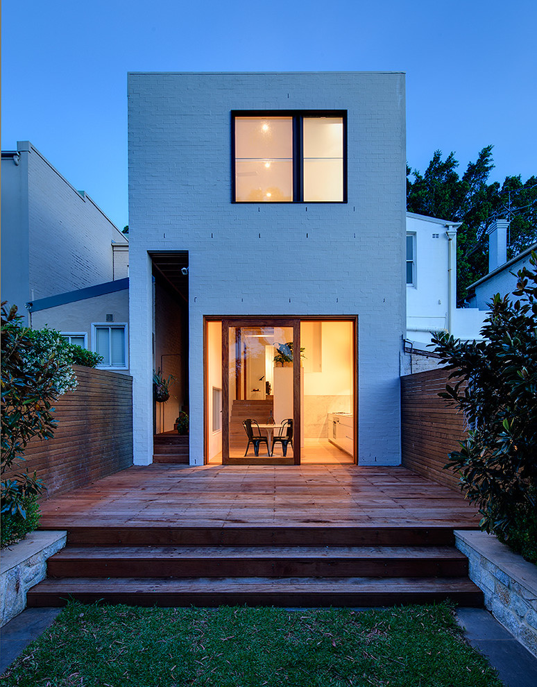 Réalisation d'une façade de maison blanche minimaliste en brique de taille moyenne et à un étage avec un toit plat.