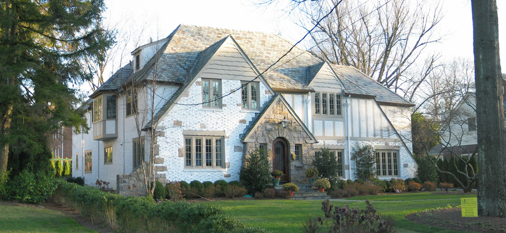 Large elegant white three-story mixed siding house exterior photo in New York with a hip roof and a shingle roof