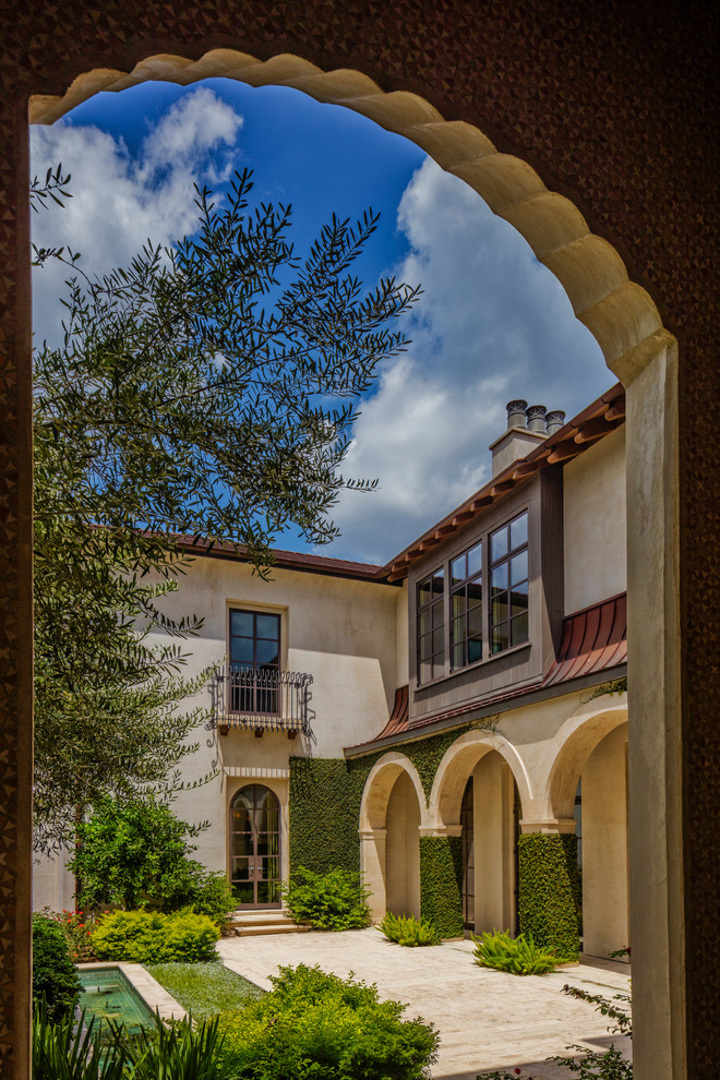 Example of a huge tuscan beige two-story stucco house exterior design in Houston with a hip roof and a tile roof