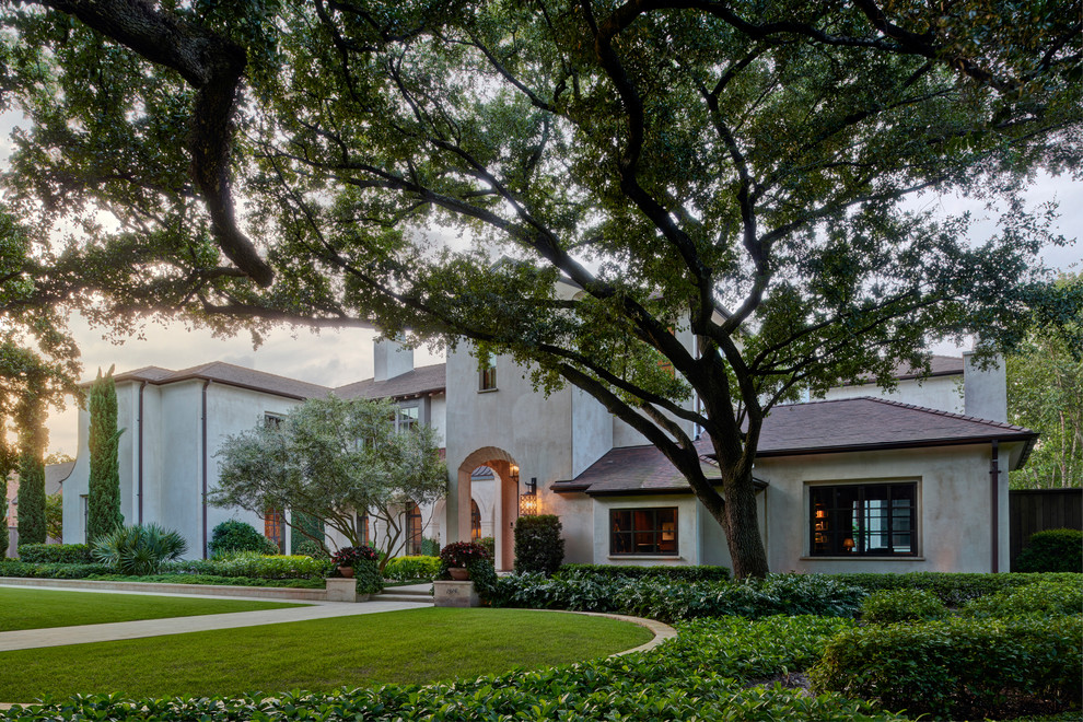 Huge tuscan beige two-story stucco house exterior photo in Houston with a hip roof and a tile roof