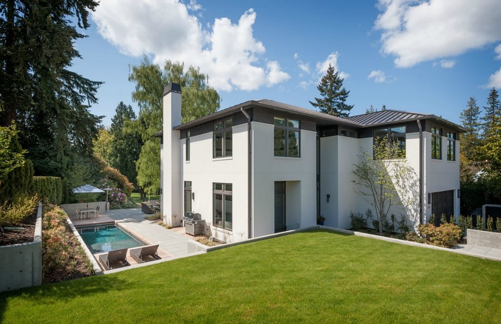 Cette image montre une grande façade de maison blanche minimaliste en stuc à deux étages et plus avec un toit à quatre pans.