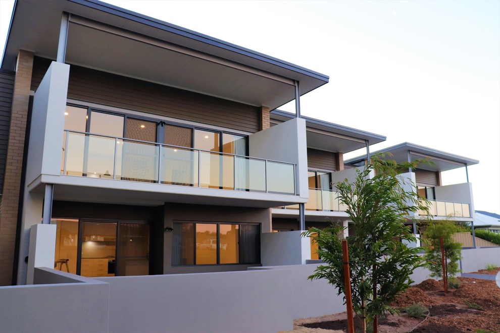 This is an example of a large and beige contemporary two floor brick flat in Perth with a flat roof and a metal roof.