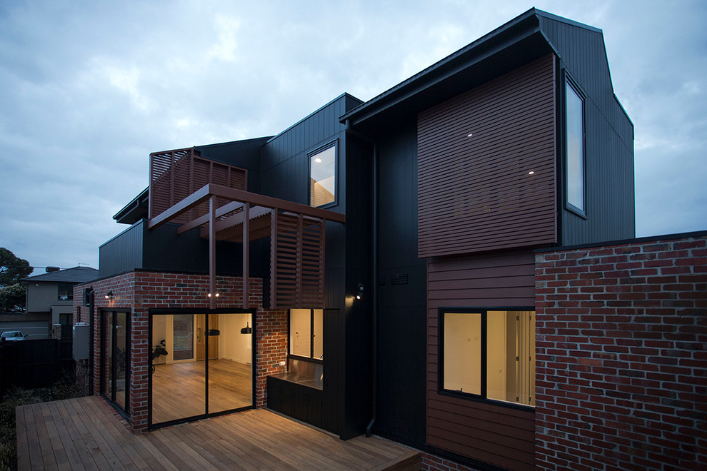 Diseño de fachada de casa negra contemporánea de tamaño medio de dos plantas con revestimiento de madera, tejado a dos aguas y tejado de metal
