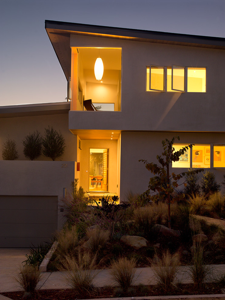 Ejemplo de fachada beige minimalista grande de dos plantas con revestimiento de estuco y tejado de un solo tendido