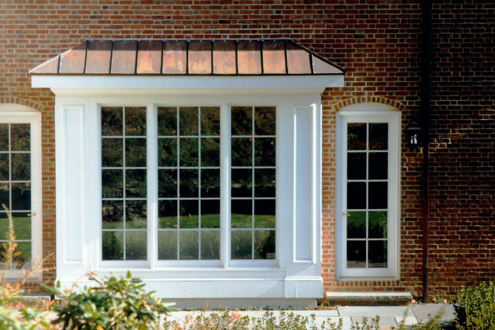 Large traditional red two-story brick house exterior idea in Boston with a hip roof and a metal roof