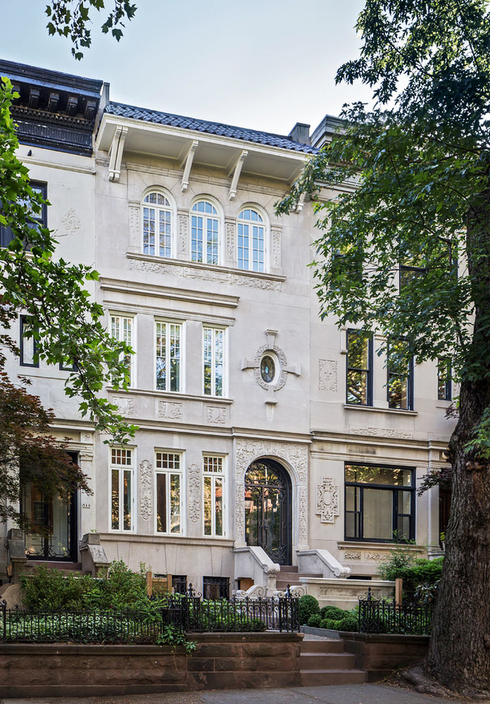 Photo of a gey classic terraced house in New York with three floors, a pitched roof and a tiled roof.