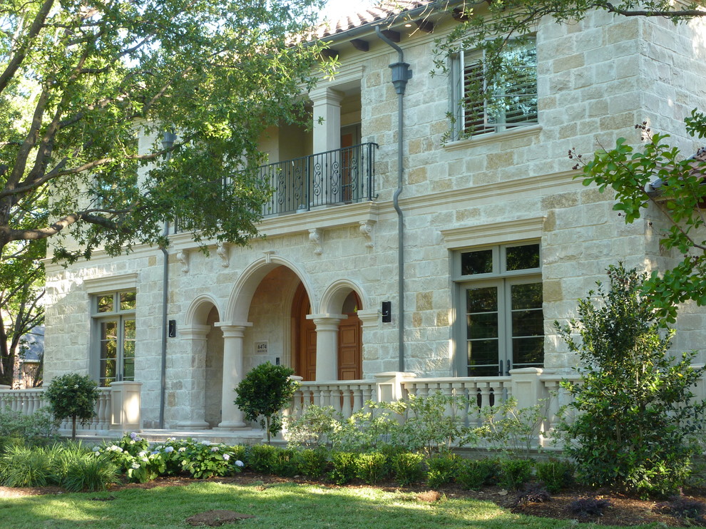 Large mediterranean beige two-story stone house exterior idea in Dallas with a hip roof and a tile roof