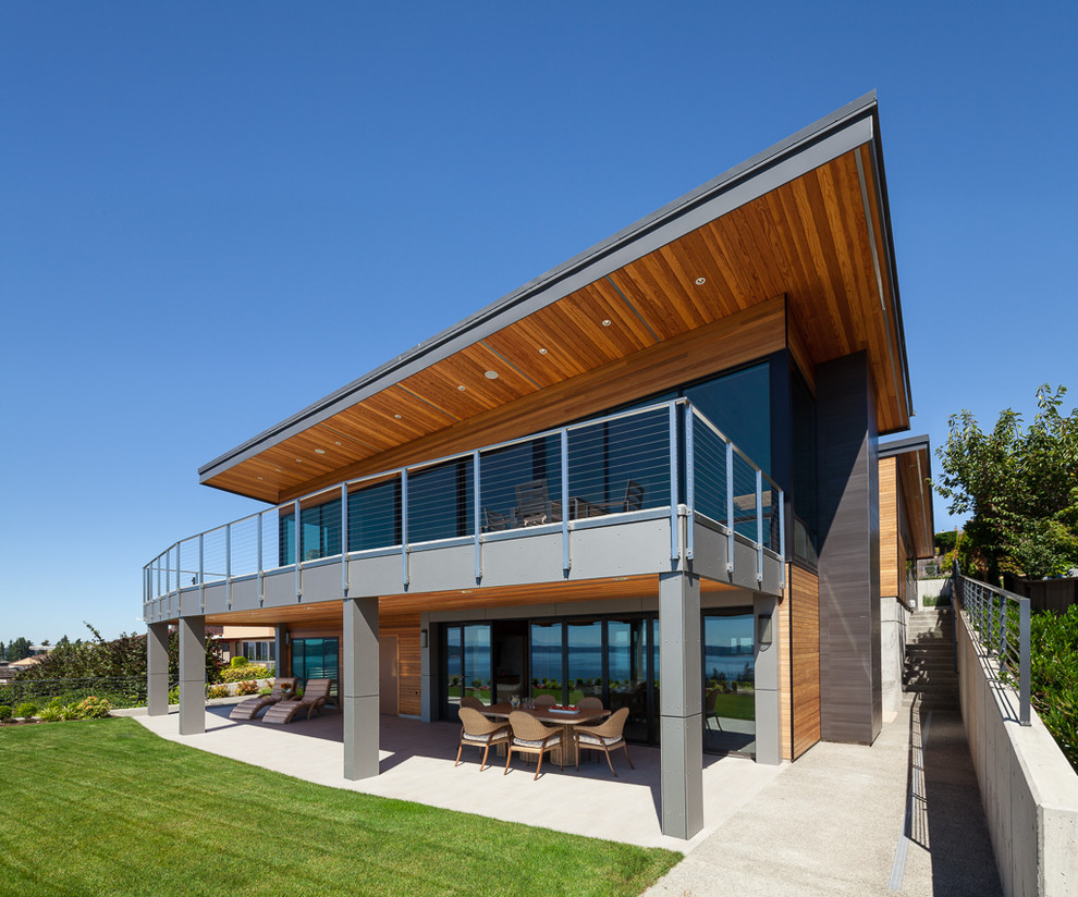 Réalisation d'une grande façade de maison grise design en bois à un étage avec un toit en appentis.