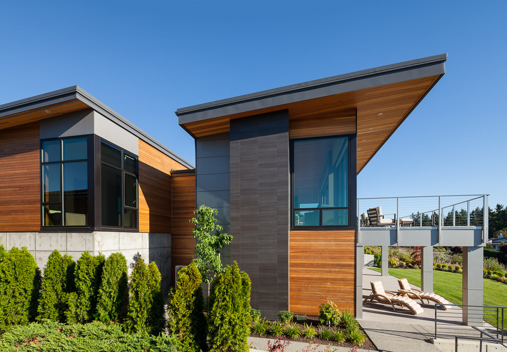 Exemple d'une grande façade de maison grise tendance en bois à un étage avec un toit en appentis et un toit en métal.