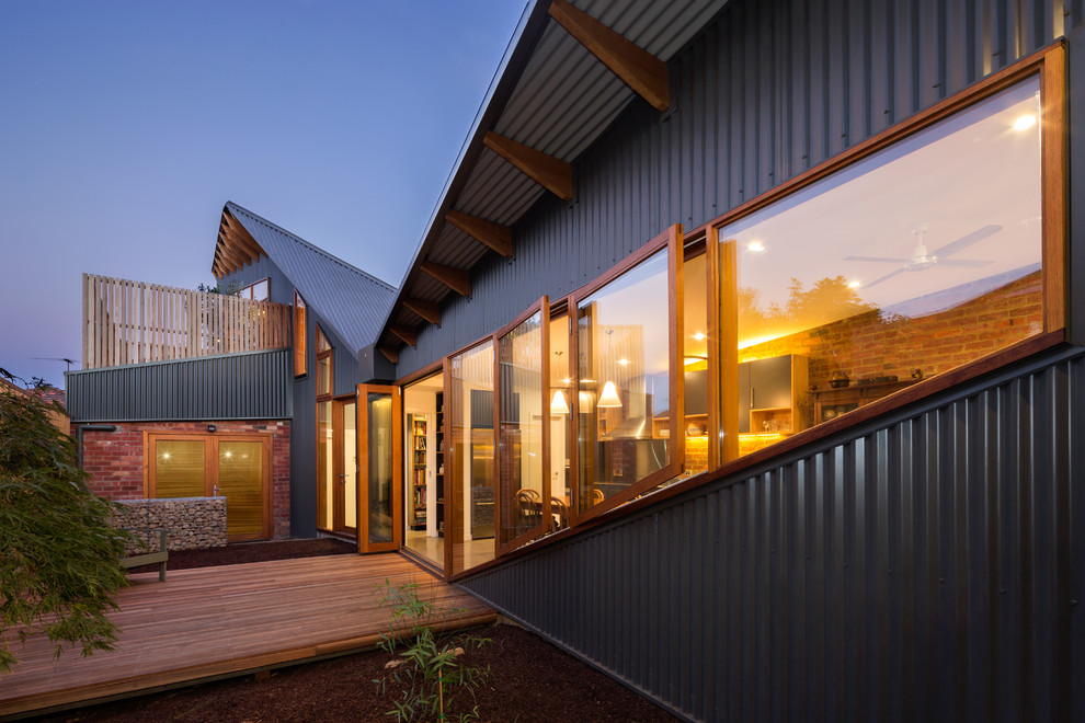 Cette photo montre une façade de maison métallique et grise tendance à un étage avec un toit en appentis.
