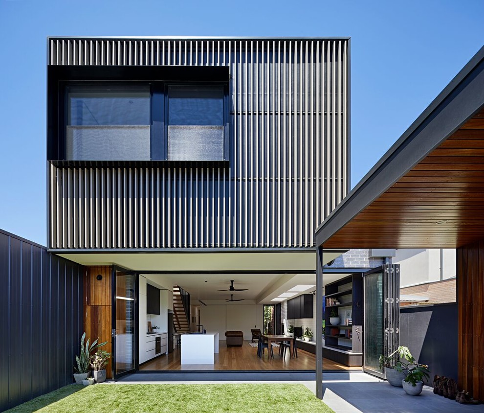 This is an example of a gey contemporary two floor detached house in Melbourne with metal cladding and a flat roof.