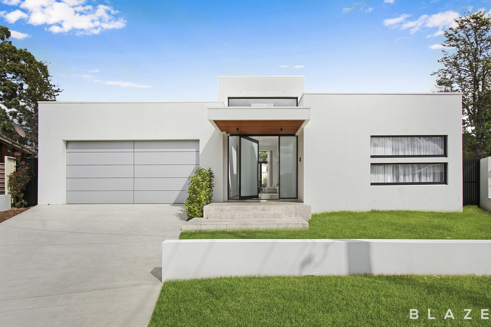 Ejemplo de fachada de casa blanca moderna de tamaño medio de una planta con revestimiento de ladrillo, tejado plano y tejado de metal