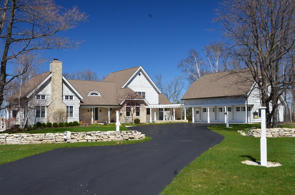 Foto della villa ampia bianca american style a due piani con rivestimento in legno, tetto a capanna e copertura in tegole