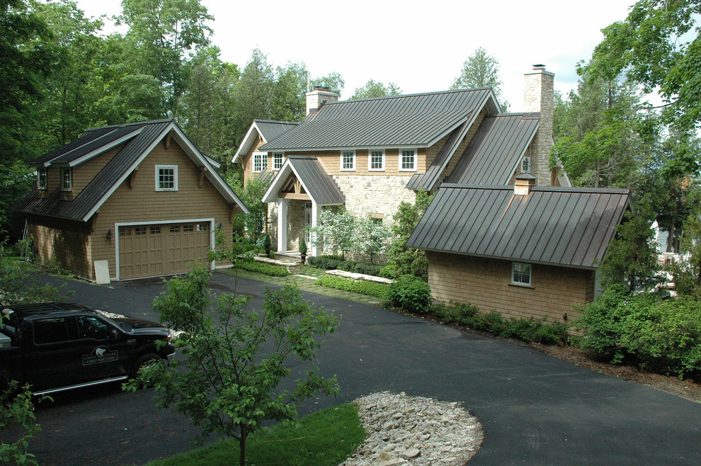 Foto della villa ampia marrone american style a due piani con rivestimento in legno, tetto a capanna, copertura in metallo o lamiera e abbinamento di colori