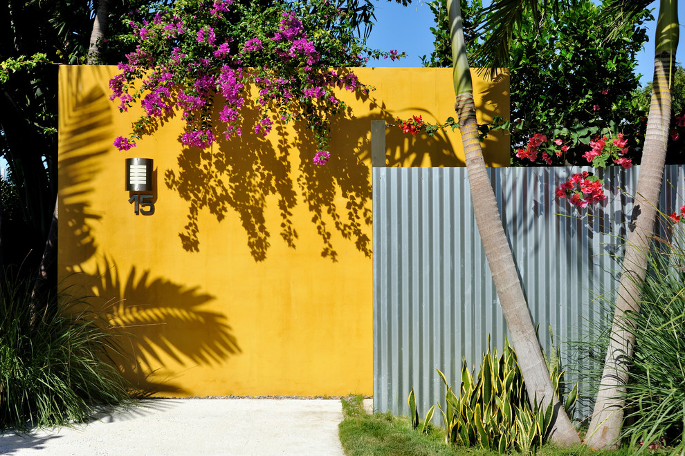 Réalisation d'une façade de maison jaune design avec un revêtement mixte.