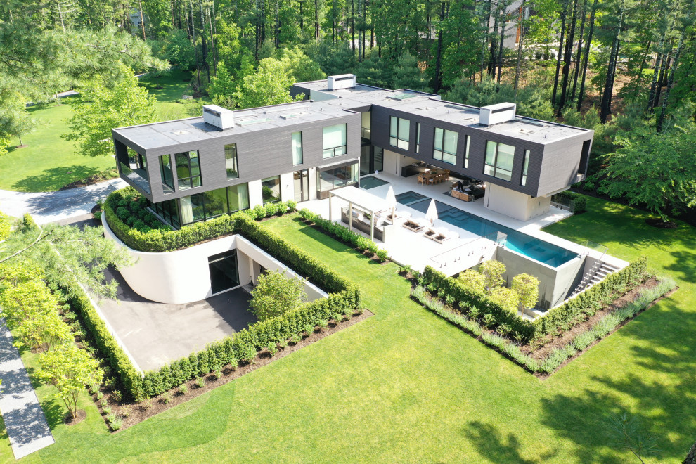 Réalisation d'une grande façade de maison noire minimaliste à un étage avec un revêtement mixte et un toit plat.