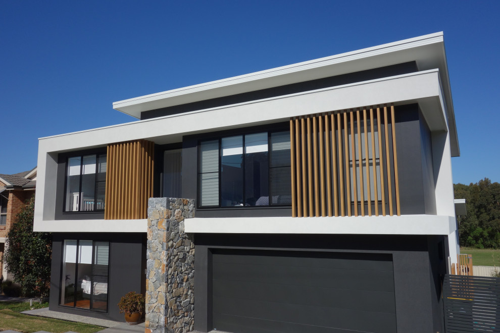Großes, Zweistöckiges Einfamilienhaus mit schwarzer Fassadenfarbe, Flachdach und Blechdach in Wollongong