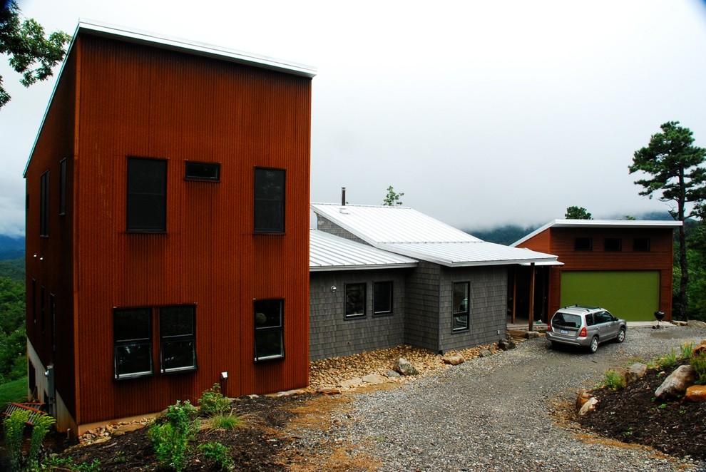 Foto della facciata di una casa contemporanea con rivestimenti misti e terreno in pendenza