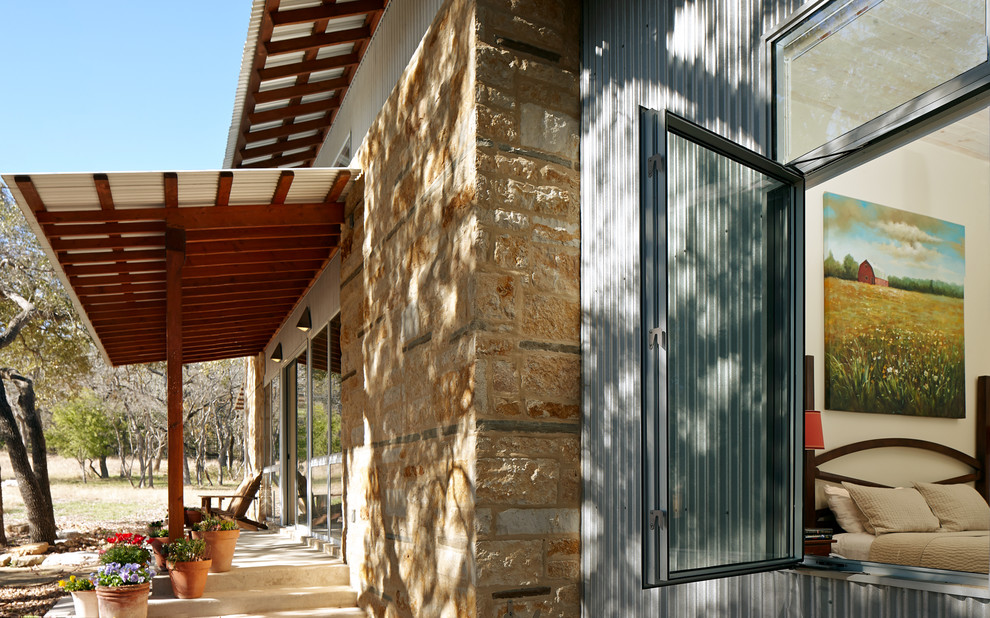 Photo of a small contemporary bungalow house exterior in Austin with stone cladding and a pitched roof.