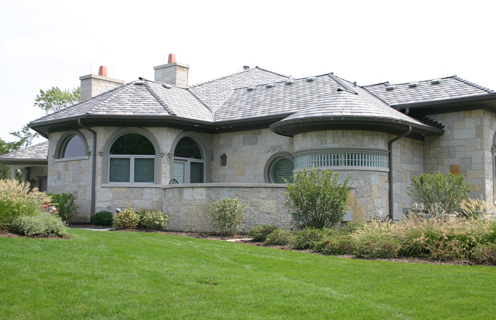 Diseño de fachada beige contemporánea grande de dos plantas con revestimiento de piedra y tejado a cuatro aguas