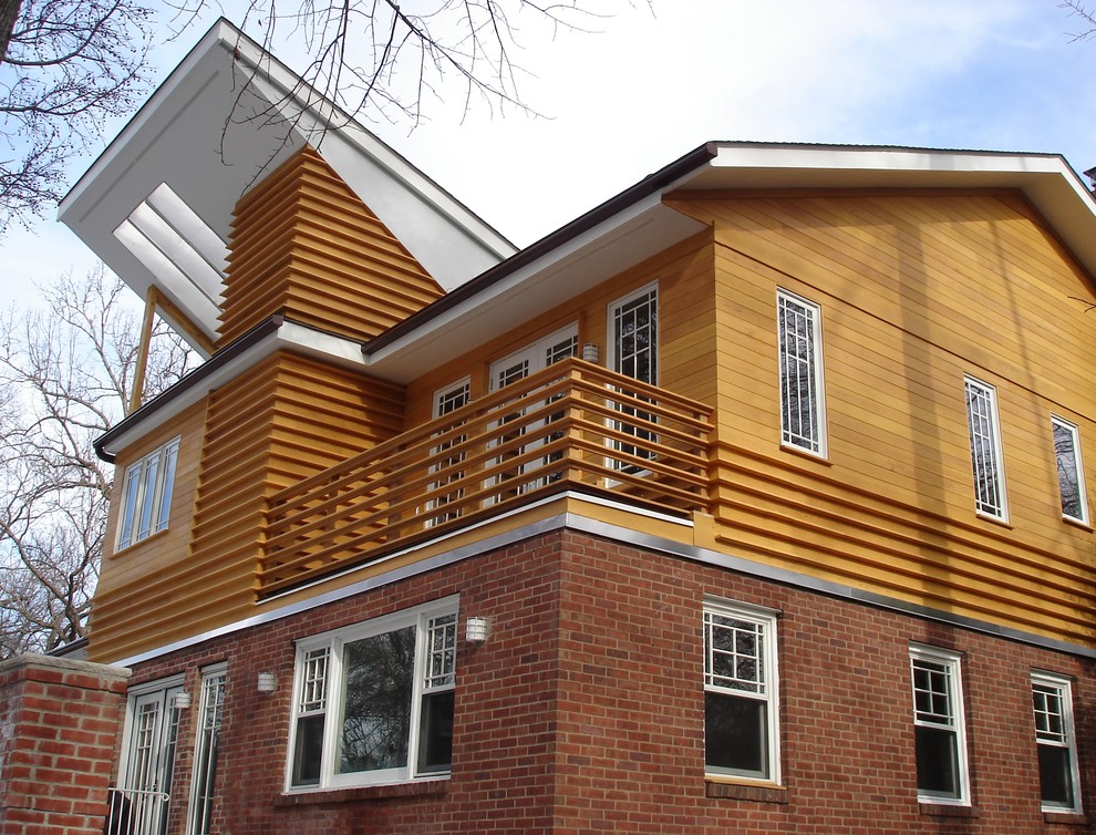 This is an example of a medium sized modern split-level house exterior in New York with wood cladding and a hip roof.