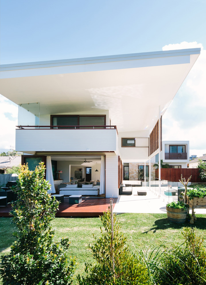 Réalisation d'une façade de maison blanche design à un étage avec un toit en appentis.