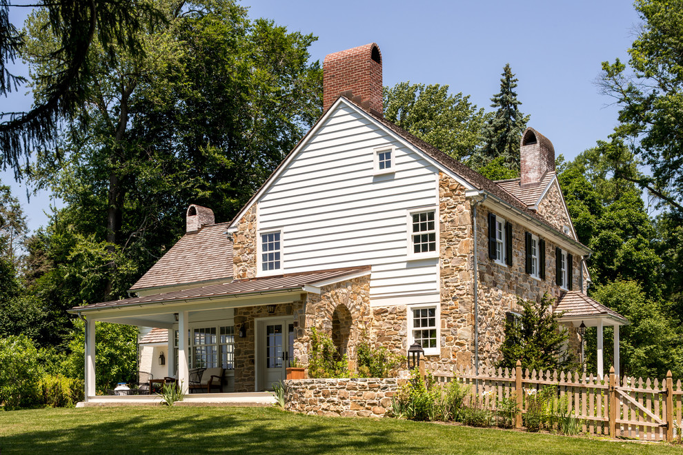 Cette image montre une grande façade de maison marron rustique à un étage avec un revêtement mixte, un toit à deux pans et un toit mixte.