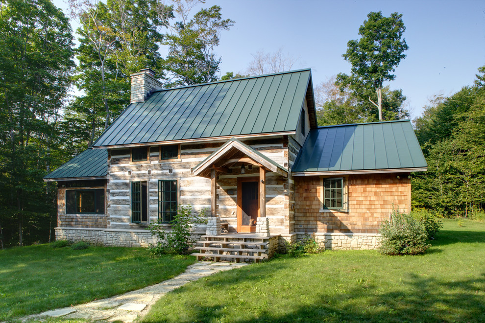 This is an example of a small rustic two floor house exterior in Milwaukee with wood cladding and a pitched roof.