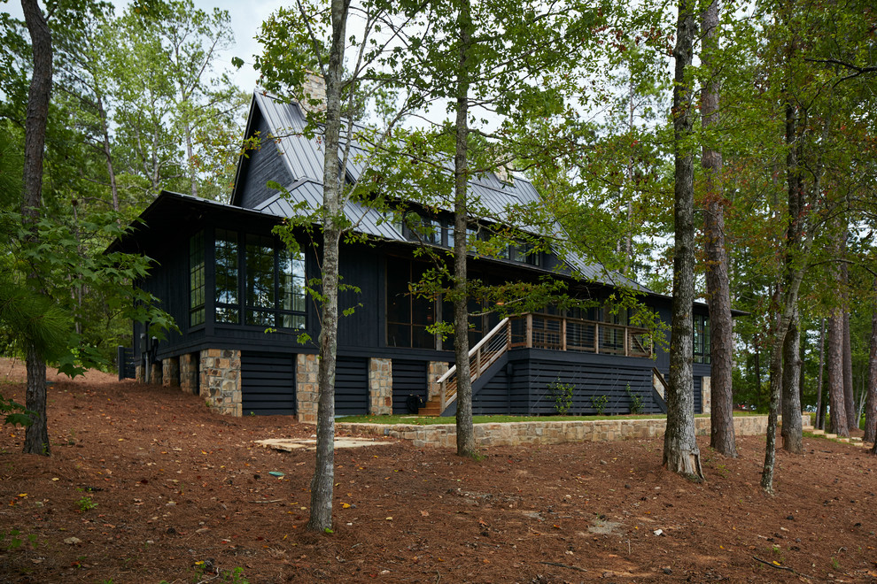 На фото: большой, двухэтажный, деревянный, черный частный загородный дом в стиле рустика с двускатной крышей и металлической крышей