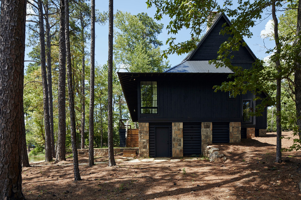 Aménagement d'une grande façade de maison noire montagne en bois à un étage avec un toit à deux pans et un toit en métal.