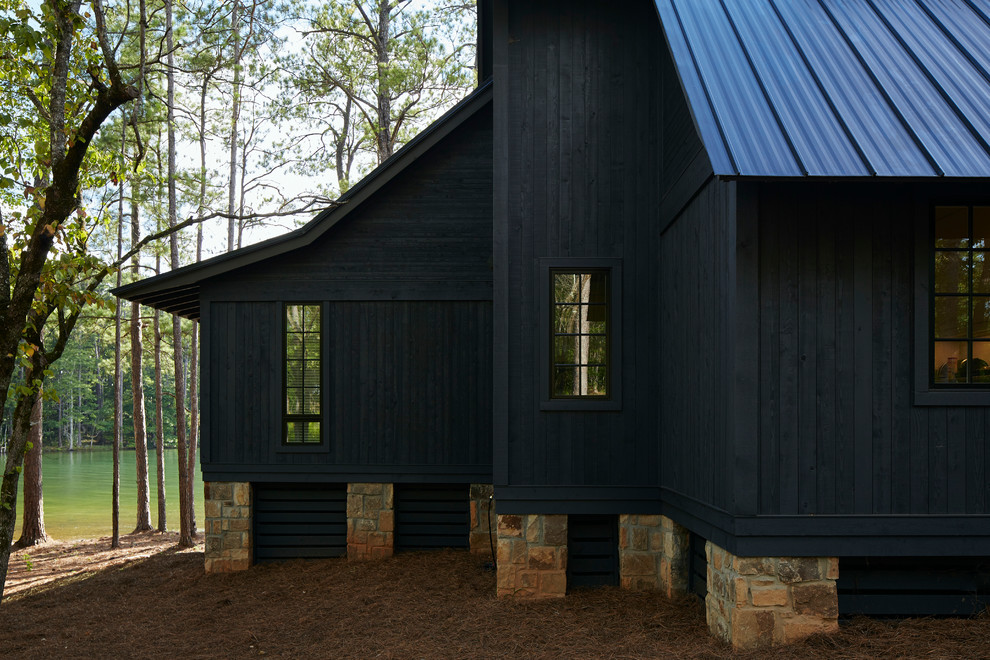Пример оригинального дизайна: большой, двухэтажный, деревянный, черный частный загородный дом в стиле рустика с двускатной крышей и металлической крышей для охотников