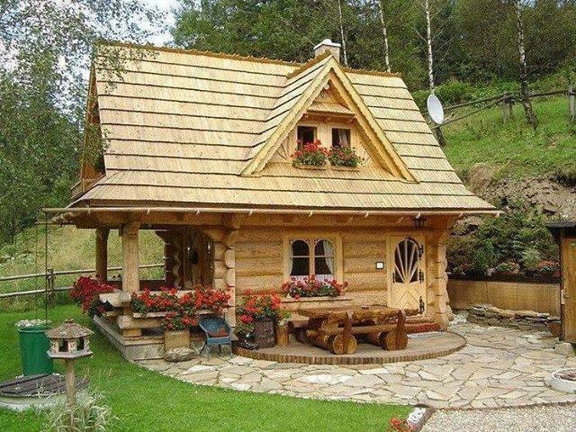 Esempio della villa piccola marrone rustica a due piani con rivestimento in legno, tetto a capanna e copertura a scandole