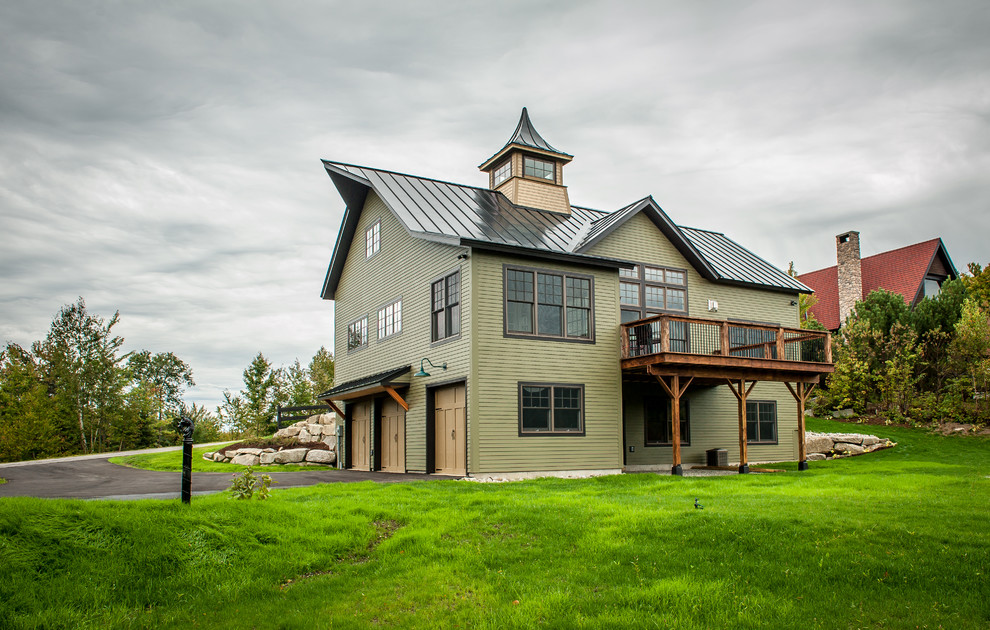На фото: двухэтажный, деревянный, зеленый частный загородный дом среднего размера в стиле фьюжн с двускатной крышей и металлической крышей с