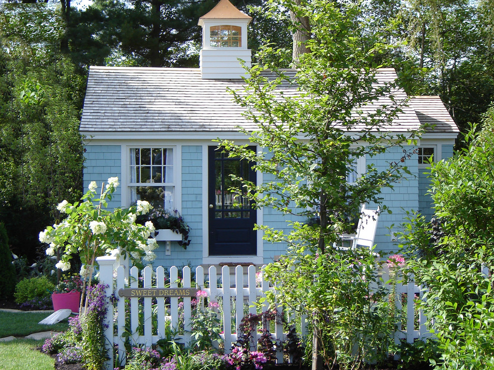 Réalisation d'une petite façade de maison bleue style shabby chic en bois de plain-pied avec un toit en appentis.
