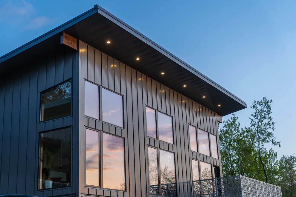 Zweistöckiges, Mittelgroßes Modernes Einfamilienhaus mit Metallfassade, grauer Fassadenfarbe, Blechdach und Pultdach in Sonstige