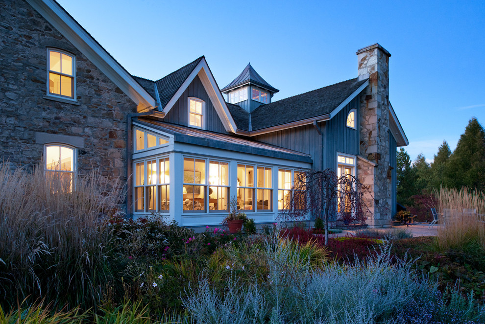 Immagine della facciata di una casa country con rivestimenti misti