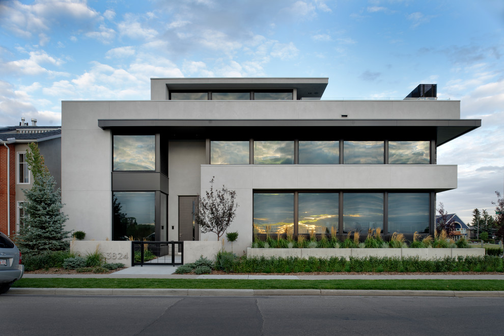 Ejemplo de fachada de casa gris moderna grande de tres plantas con tejado plano y revestimiento de hormigón