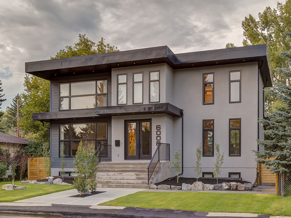 Идея дизайна: большой, двухэтажный, серый дом в стиле модернизм с облицовкой из цементной штукатурки и плоской крышей