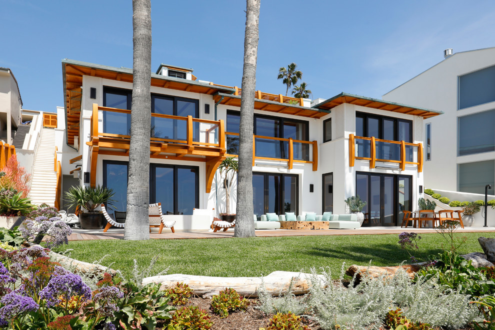 Diseño de fachada de casa blanca marinera grande a niveles con revestimiento de estuco y tejado de metal