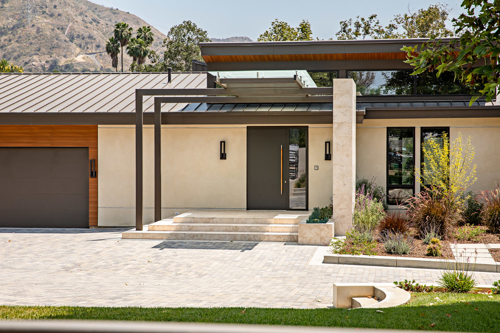 Ispirazione per la facciata di una casa beige moderna a un piano di medie dimensioni con rivestimento in stucco e copertura in metallo o lamiera
