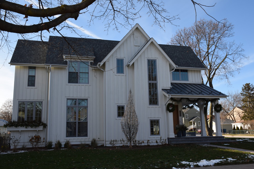 Foto della villa grande bianca country a due piani con rivestimento in legno, tetto a capanna e copertura mista