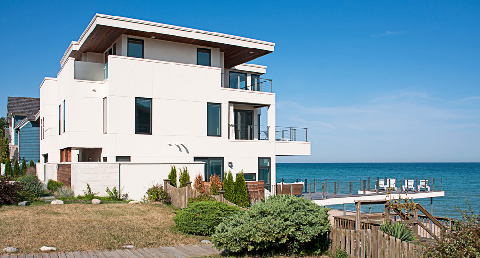 Идея дизайна: огромный дом в морском стиле с разными уровнями и облицовкой из цементной штукатурки