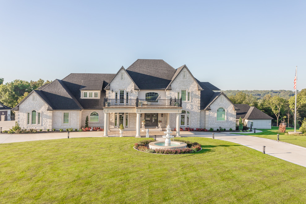 Large elegant white two-story stone house exterior photo in Other with a hip roof and a shingle roof