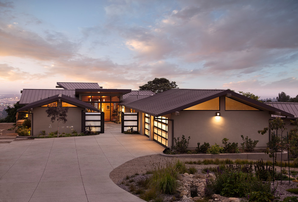 Example of a mid-sized trendy beige one-story stucco exterior home design in Los Angeles with a metal roof