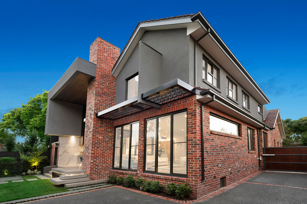 Photo of a large and red contemporary two floor brick house exterior in Melbourne with a pitched roof.