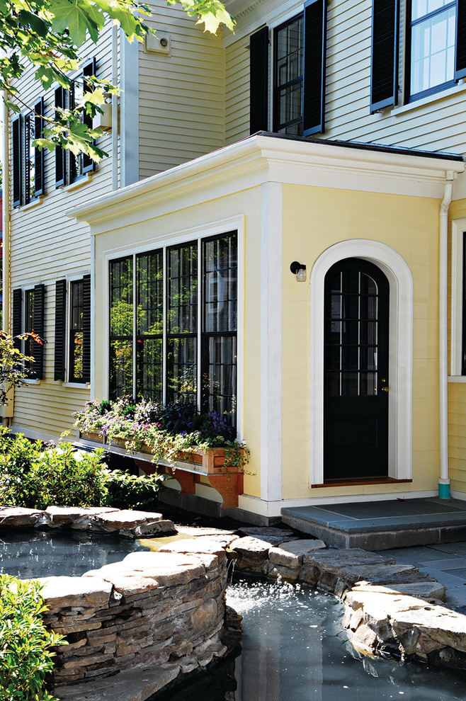 Cette image montre une grande façade de maison jaune traditionnelle à deux étages et plus.