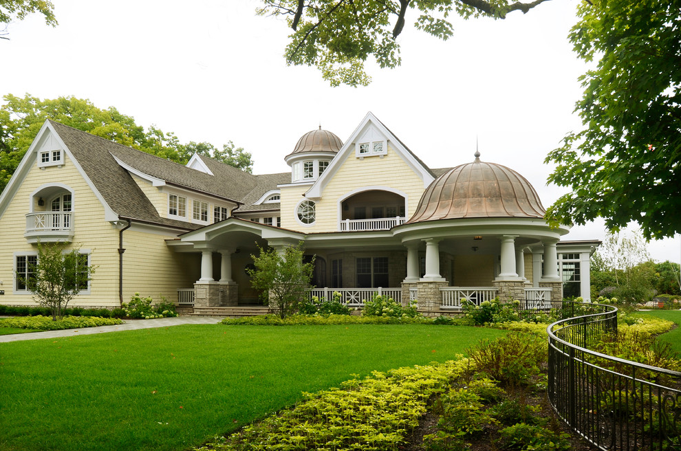Esempio della villa ampia gialla american style a tre piani con rivestimenti misti, tetto a capanna e copertura a scandole