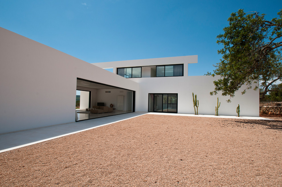 На фото: большой, двухэтажный, белый дом в средиземноморском стиле с облицовкой из цементной штукатурки и плоской крышей с