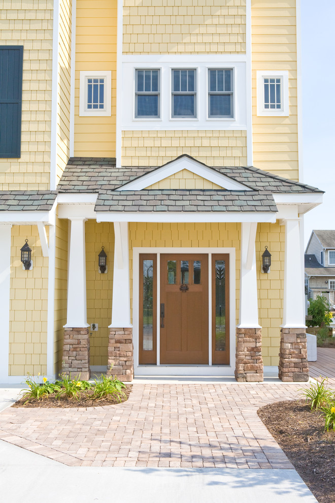 Large transitional yellow three-story vinyl house exterior photo in Other with a hip roof and a mixed material roof