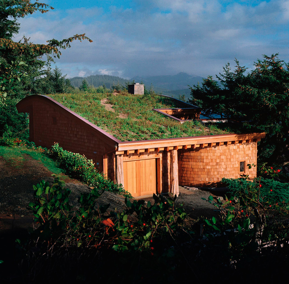 Aménagement d'une façade de maison marron montagne en bois de taille moyenne et à un étage avec un toit en appentis et un toit végétal.